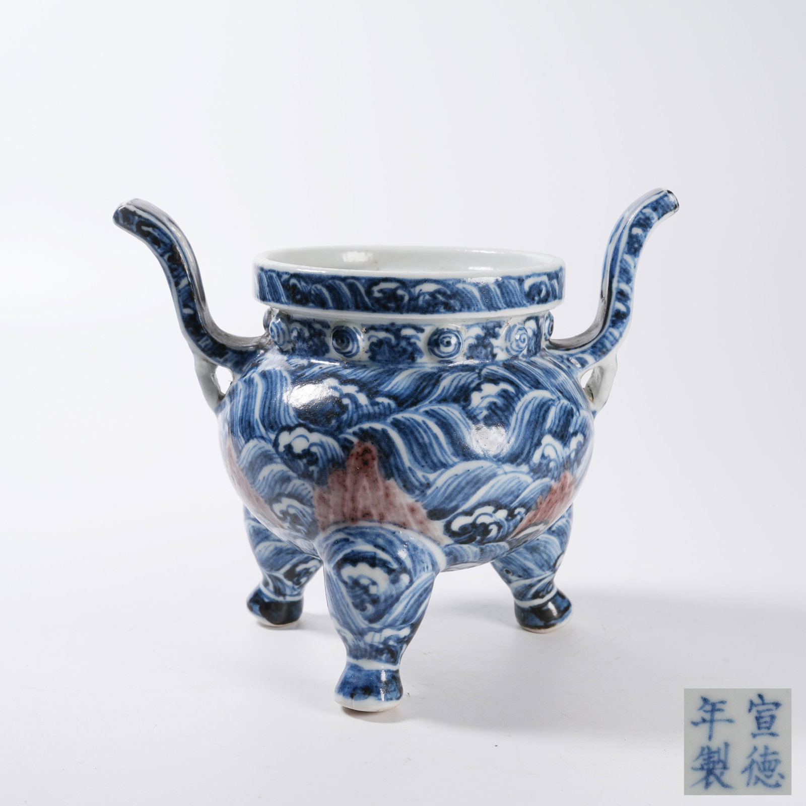 A BLUE AND WHITE UNDERGLAZE RED TRIPOD CENSER WITH COURT HAT EARS AND RIVER CLIFF AND SEA WAVE: Blue and White Underglaze Red Tripod Censer with Court Hat Ears and River Cliff and Sea Wave Pattern