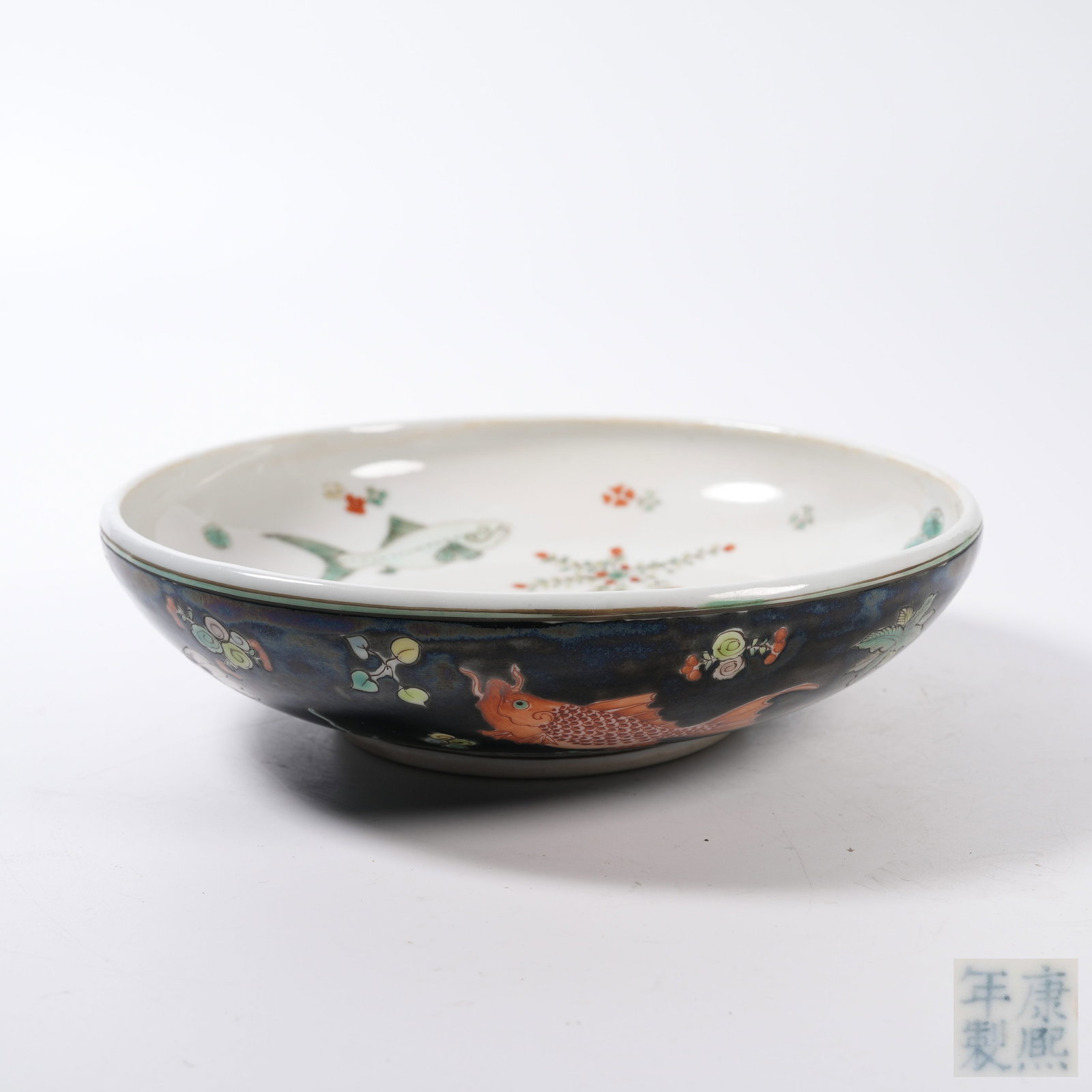 A FAMILLE ROSE PLATE WITH FISH AND AQUATIC WEED PATTERN ON BLACK GROUND: Famille Rose Plate with Fish and Aquatic Weed Pattern on Black Ground
