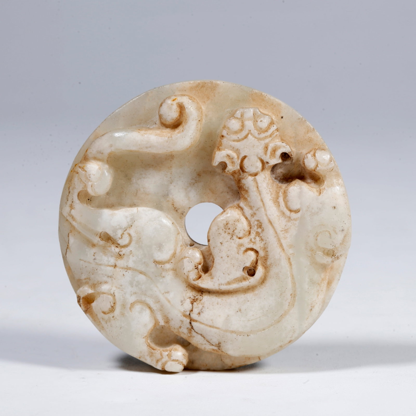 A ANCIENT JADE BI-DISC CARVED WITH DRAGON PATTERN: Ancient jade bi-disc carved with dragon pattern
