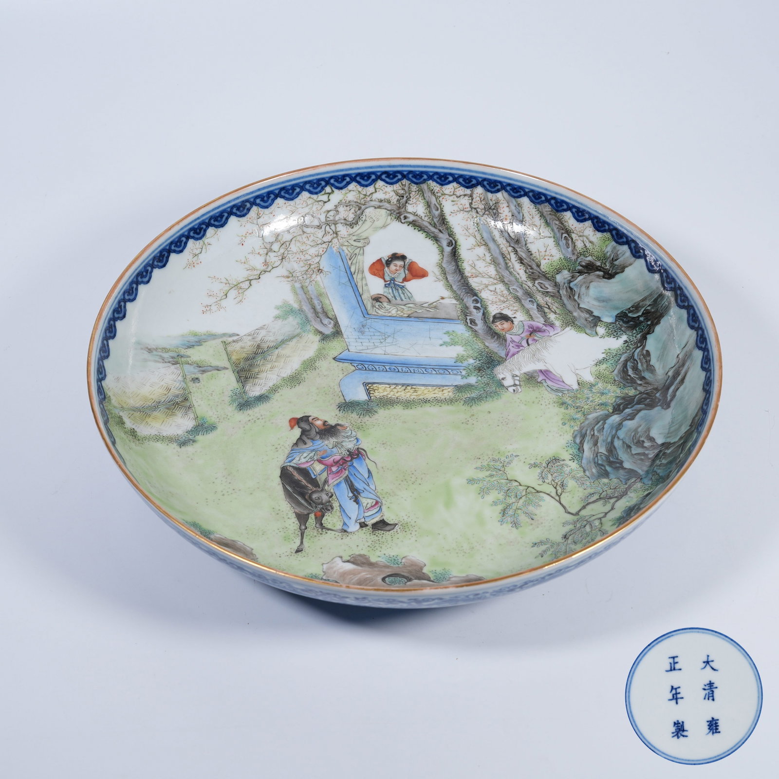 A PLATE WITH INNER FAMILLE-ROSE FIGURE-STORY DESIGN AND OUTER BLUE-AND-WHITE FLORAL PATTERN: Plate with inner famille-rose figure-story design and outer blue-and-white floral pattern