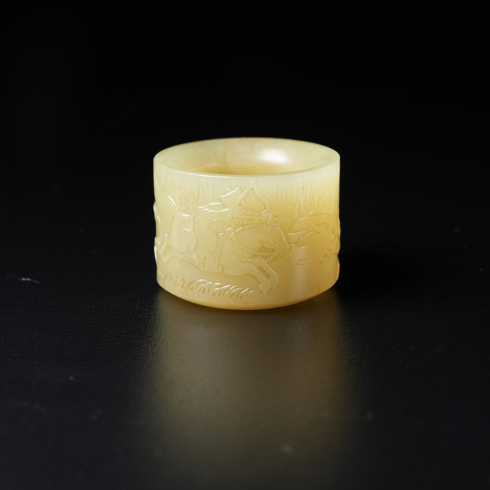 A YELLOW HETIAN JADE THUMB RING WITH HUNTING SCENE: Yellow Hetian jade thumb ring with hunting scene
