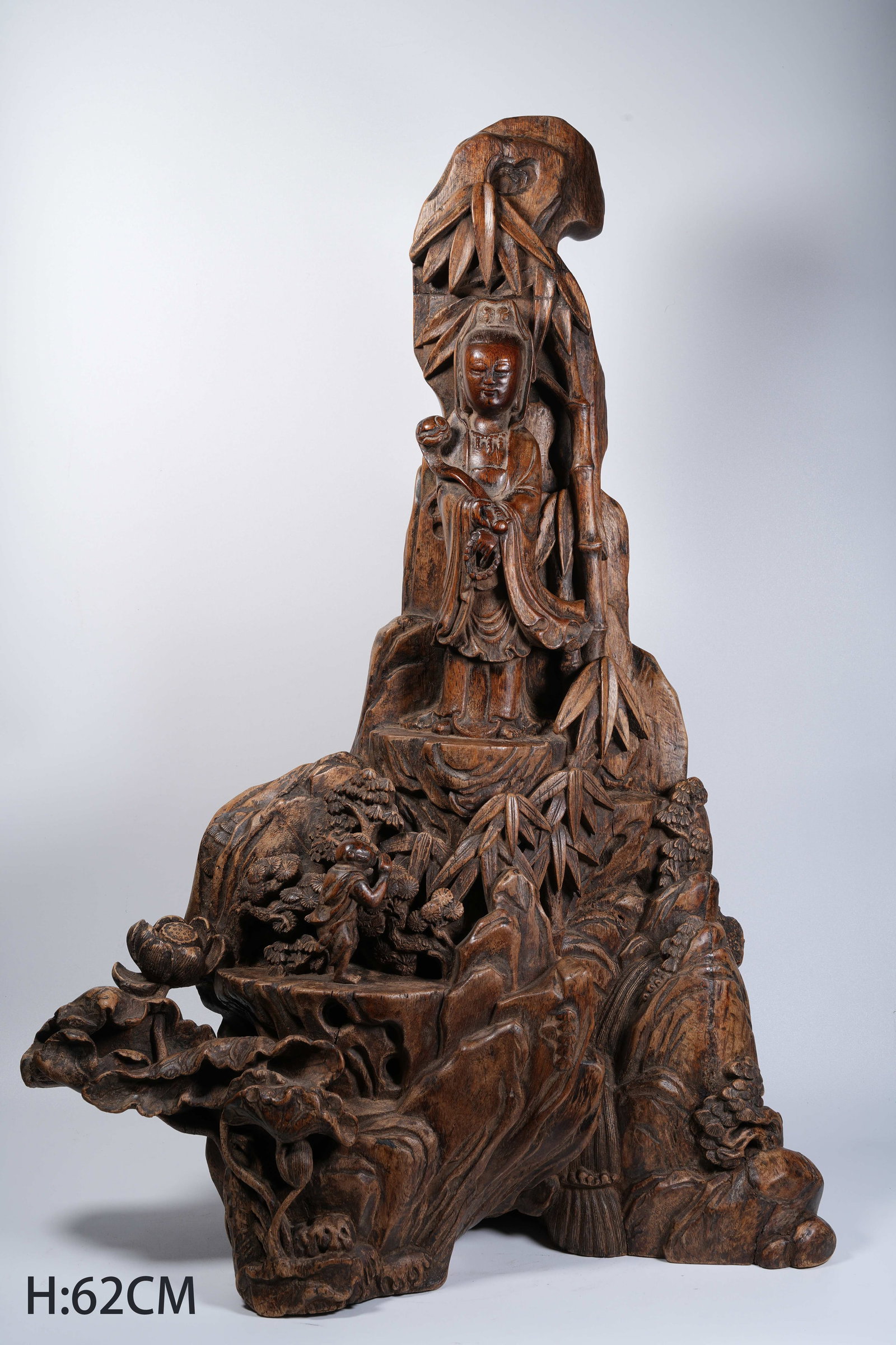 A AGARWOOD MOUNTAIN-STYLE ORNAMENT WITH BOY WORSHIPPING GUANYIN MOTIF: Agarwood mountain-style ornament with boy worshipping Guanyin motif