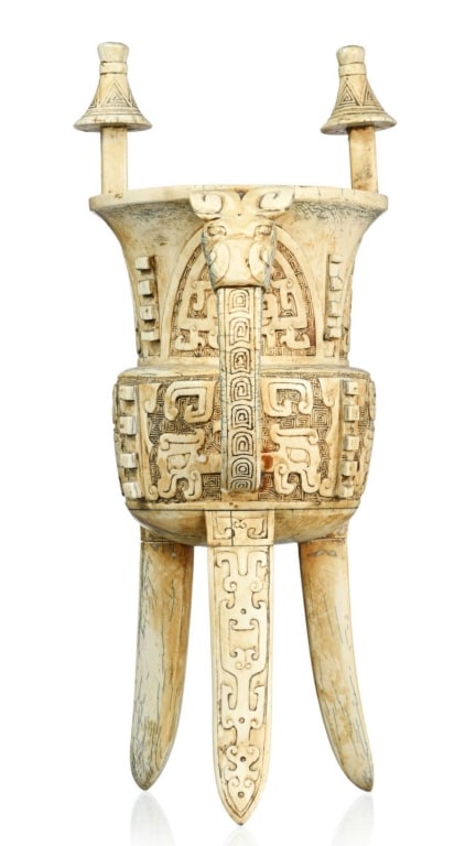17th intricately carved hard carving elephant tusk Chinese Jue-form vessel: 17th hard carving elephant tusk intricately carved Chinese Jue-form vessel tripod, decoration of taotie , leiwen and raised edges, with a handle decorated the rim surmounted by two appendages, h. 34 c