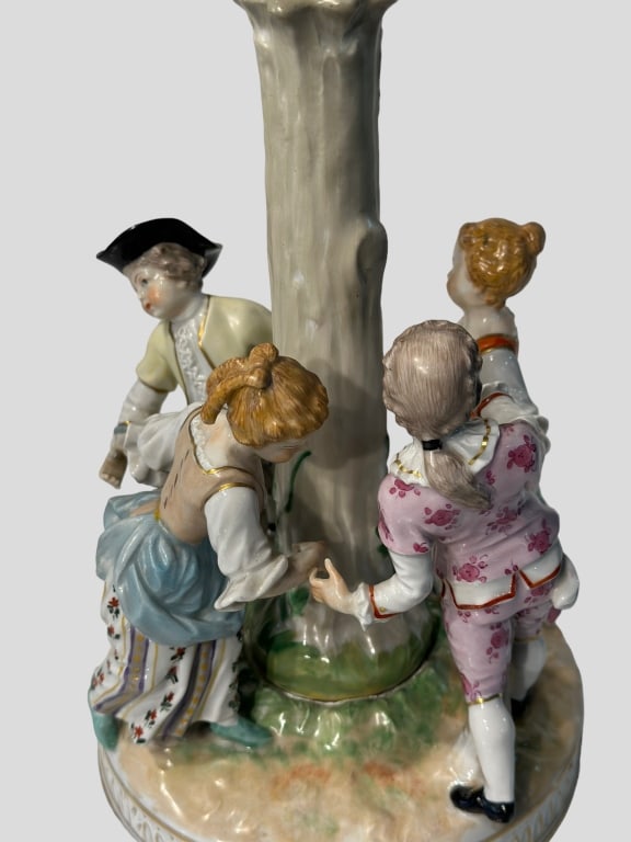 Dresden Porcelain Figures of Aristocrats A beautifully hand-painted Dresden porcelain figural group,: A beautifully hand-painted Dresden porcelain figural group, depicting four 18th-century courtiers ? two ladies and two gentlemen ? elegantly dressed and gathered around a tree trunk, symbolizing a fes