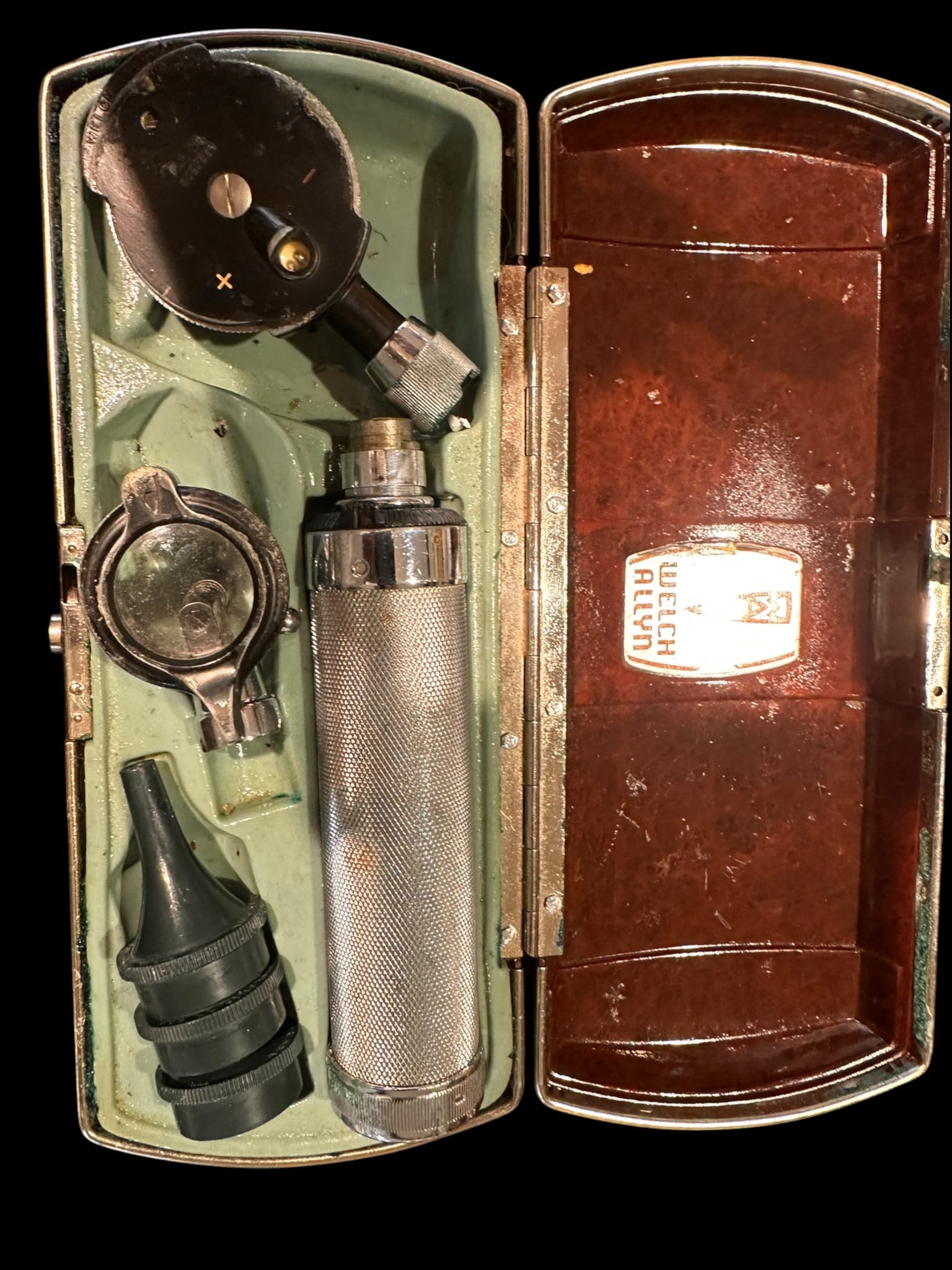 A vintage Welch Allyn diagnostic otoscope set, housed in its original molded Bakelite case.: A vintage Welch Allyn diagnostic otoscope set, housed in its original molded Bakelite case. The hinged case opens to reveal a knurled metal battery handle with interchangeable examination heads and at