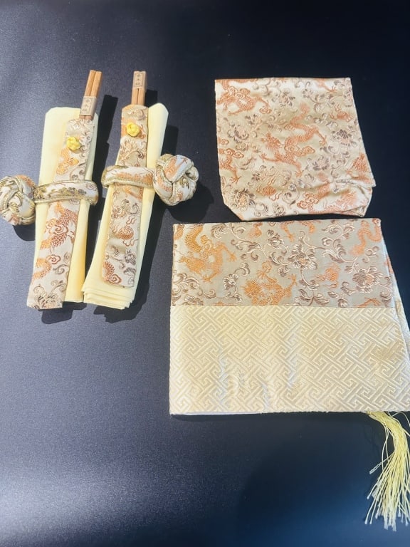 set for two chinese table napkins ring chopsticks A set of finely crafted Japanese silk brocade: A set of finely crafted Japanese silk brocade items featuring intricate gold-thread designs of dragons and clouds on cream and gold backgrounds. The set includes two chopstick holders with decorative