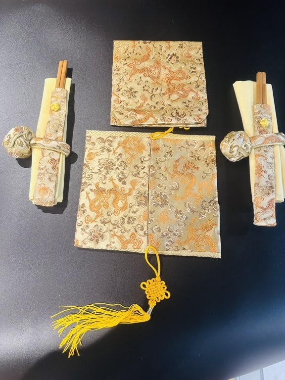 set for two chinese table napkins ring chopsticks A set of finely crafted Japanese silk brocade: A set of finely crafted Japanese silk brocade items featuring intricate gold-thread designs of dragons and clouds on cream and gold backgrounds. The set includes two chopstick holders with decorative