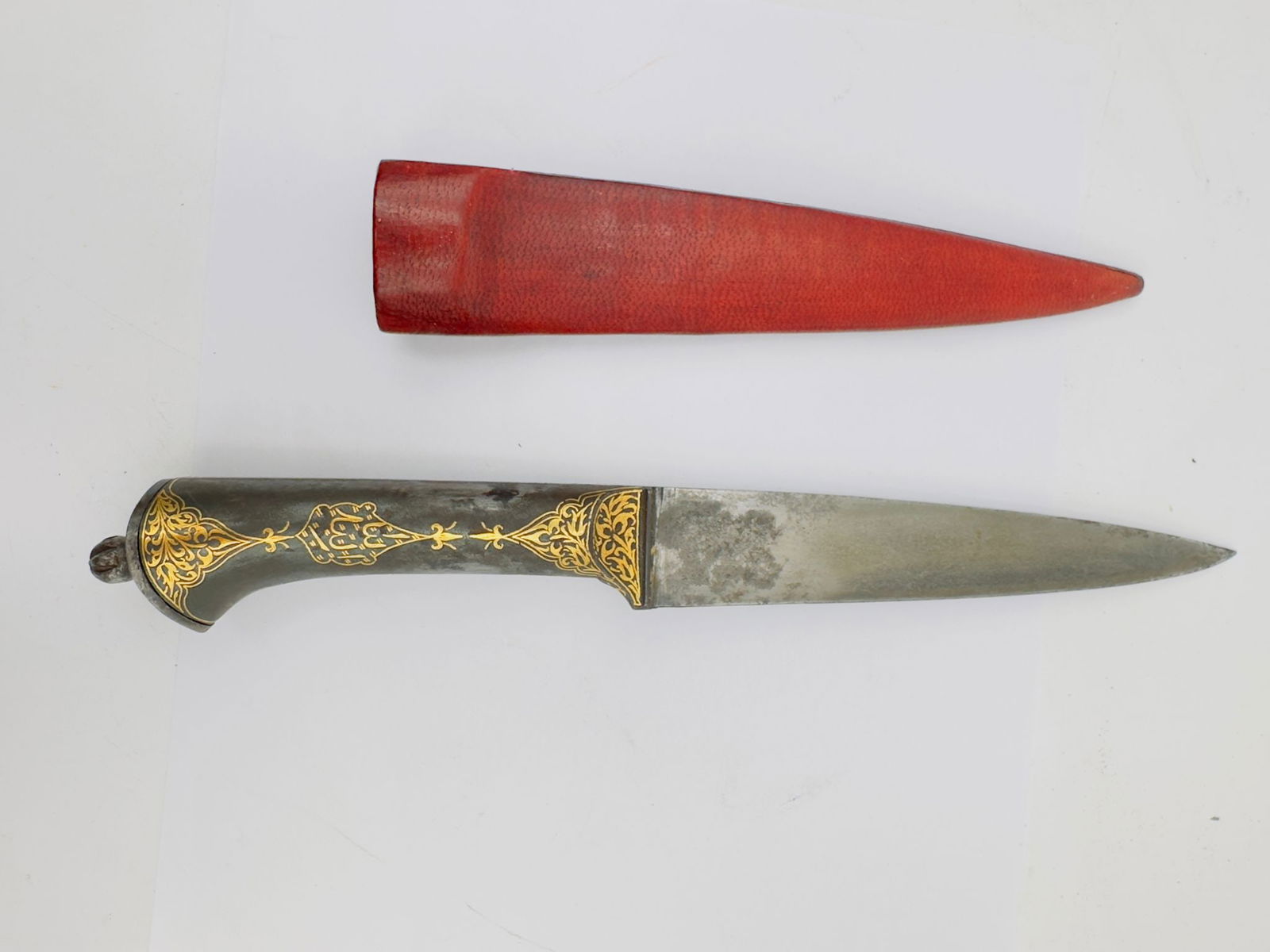 Persian qajar Islamic Gilded Steel Dagger with Gold Inlay and Leather Sheath: An elegant Islamic dagger featuring a straight steel blade and a finely decorated hilt enriched with intricate gold inlay (damascening). The handle is adorned with scrolling vegetal and geometric moti