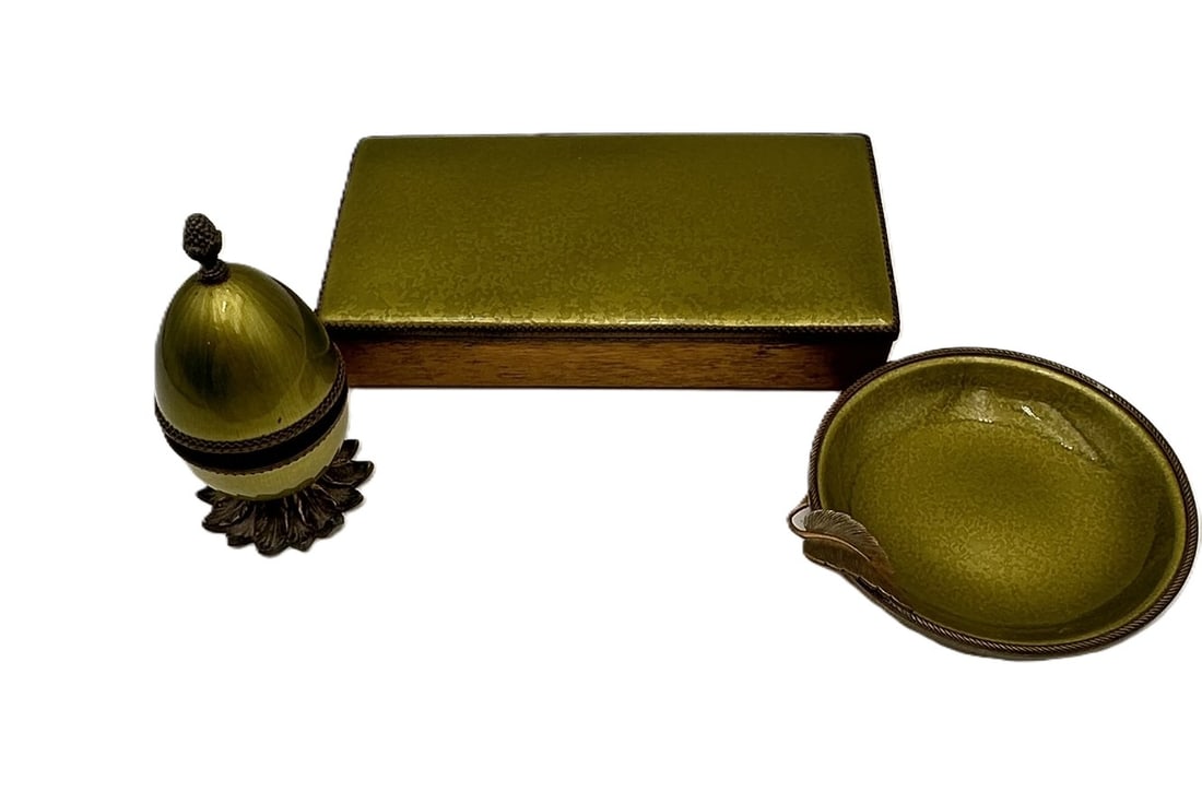 A refined Evans USA three-piece desk set comprising a rectangular lidded box, leaf-form dish, and: A refined Evans USA three-piece desk set comprising a rectangular lidded box, leaf-form dish, and egg-shaped trinket lighter on a floral base. Each piece finished in rich green guilloch? enamel with