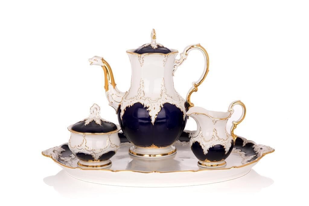 An elegant Meissen porcelain coffee service, finely executed in deep cobalt blue and enriched with: An elegant Meissen porcelain coffee service, finely executed in deep cobalt blue and enriched with heavy gilt Rococo-style scrollwork and raised white relief ornament. The set features refined modelin