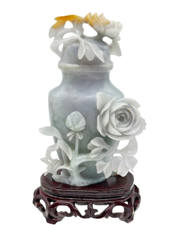 A finely carved Chinese celadon jade vase, skilfully worked in high relief with blossoming: A finely carved Chinese celadon jade vase, skilfully worked in high relief with blossoming flowers, leafy vines, and openwork details, the stone of pale celadon tone with natural russet inclusions acc