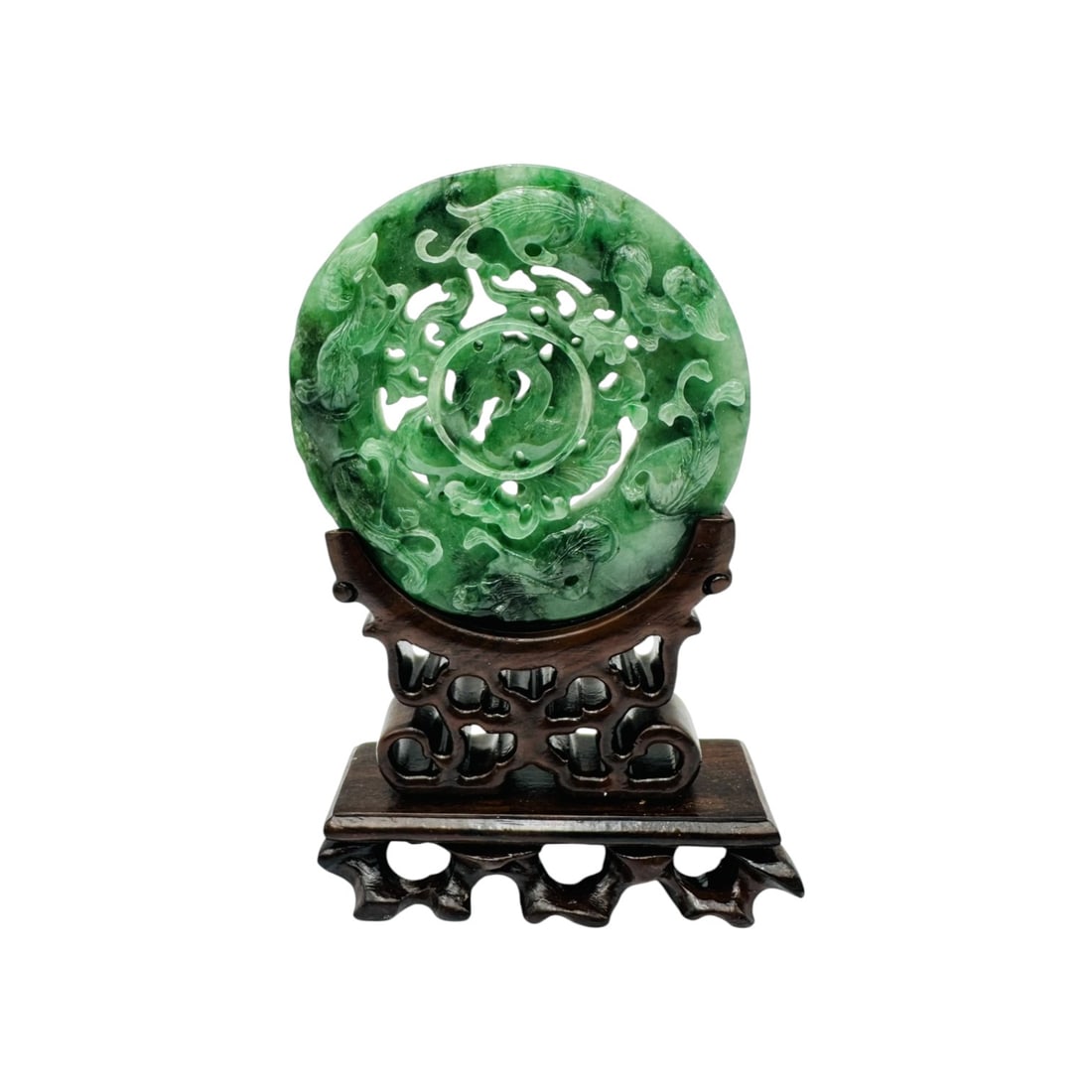 A finely carved Chinese green jade bi disc, pierced and worked in open relief with archaic scrolls: A finely carved Chinese green jade bi disc, pierced and worked in open relief with archaic scrolls and stylized mythical motifs, the stone displaying attractive variegated tones of emerald and apple g