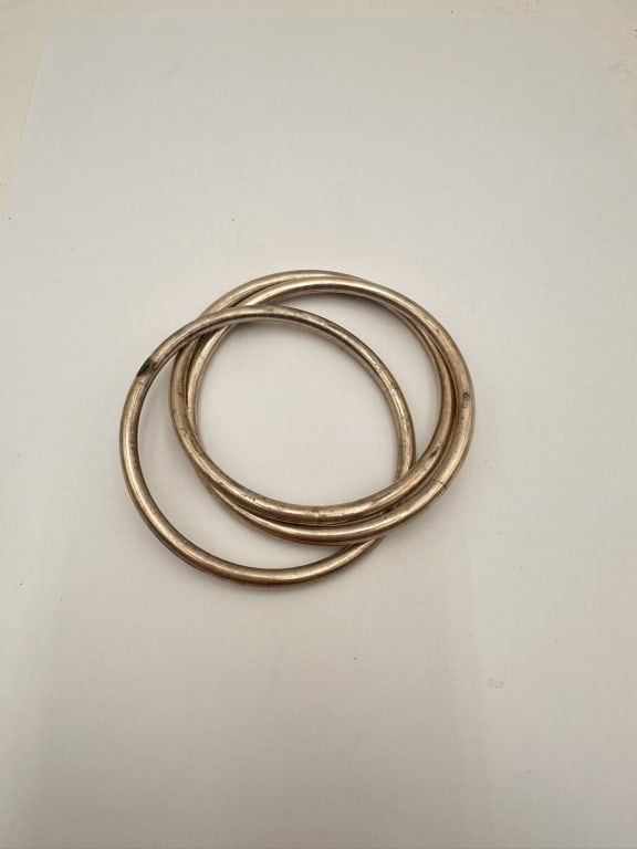 Set of Three Silver Bangles: A group of three simple and elegant circular bangles, crafted in silver. Each bracelet features a smooth, rounded form with a classic minimalist design, ideal for stacking or wearing individually.Thes