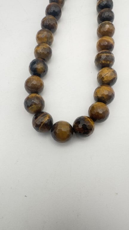 Faceted Tiger’s Eye Bead Necklace: Faceted Tiger’s Eye Bead Necklace A refined necklace composed of faceted Tiger’s Eye gemstone beads, displaying rich golden-brown tones with characteristic chatoyancy (silky, moving light effect).