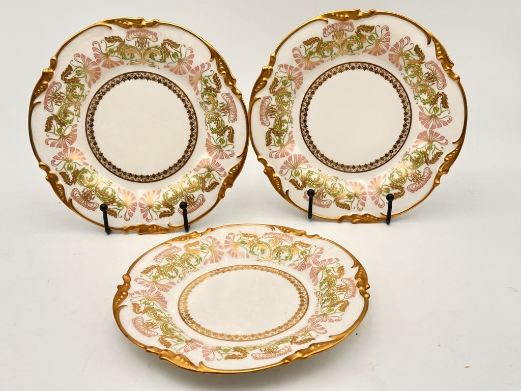 A beautiful set of three hand-decorated Limoges porcelain plates by J. Pouyat, France. Each plate: A beautiful set of three hand-decorated Limoges porcelain plates by J. Pouyat, France. Each plate features an elegant Art Nouveau?inspired border with flowing pink florals, scrolling green foliage, an
