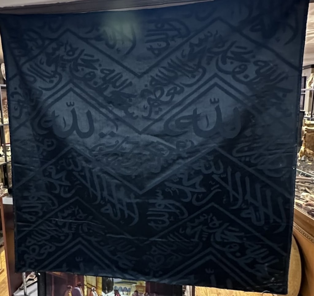 this large black silk cloth originates from the Kiswa, the iconic textile that drapes the Kaaba in: this large black silk cloth originates from the Kiswa, the iconic textile that drapes the Kaaba in Mecca, Saudi Arabia. The fabric features beautifully woven calligraphy in elegant Arabic script, trad