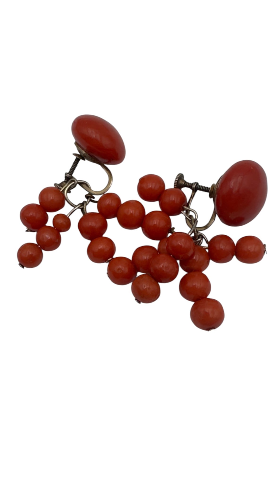 A pair of vintage earrings featuring polished coral cabochon tops suspending clusters of small: A pair of vintage earrings featuring polished coral cabochon tops suspending clusters of small natural coral beads. The earrings retain their original screw-back fittings and display the warm natural