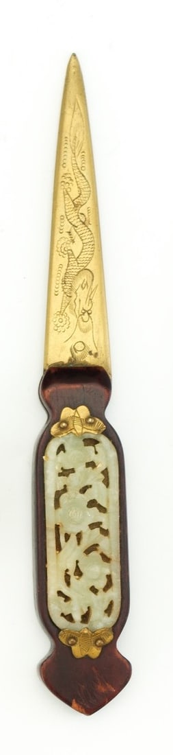 An elegant Chinese letter opener featuring a gilt brass blade finely engraved with a dragon: An elegant Chinese letter opener featuring a gilt brass blade finely engraved with a dragon chasing a flaming pearl, symbolizing power and wisdom. The handle is mounted with a pierced jade plaque depi