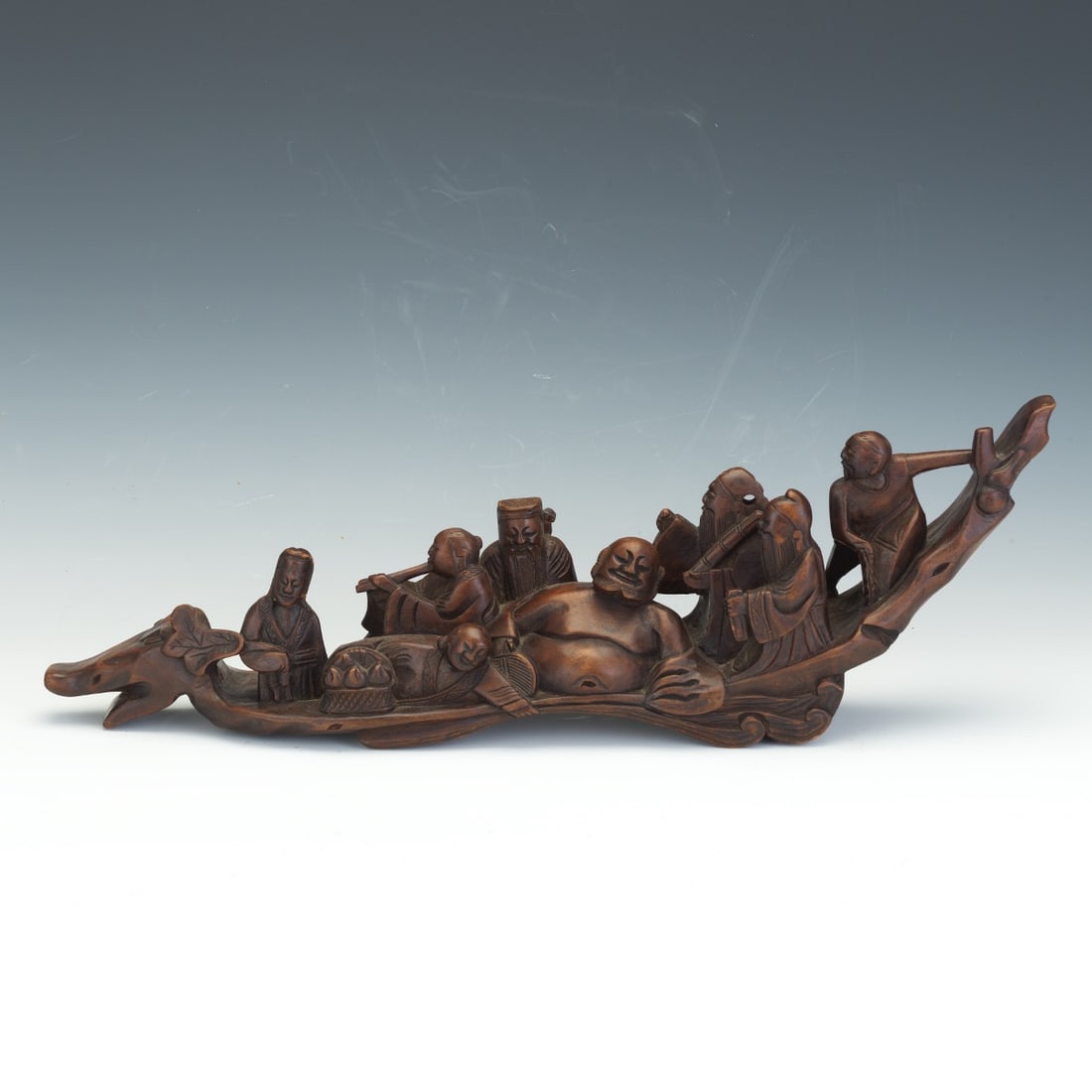 A large Chinese carved hardwood sculpture depicting the Eight Daoist Immortals (Ba Xian) aboard a: A large Chinese carved hardwood sculpture depicting the Eight Daoist Immortals (Ba Xian) aboard a dragon-headed boat. The well rendered figures include recognizable attributes such as a fan, flute, sc