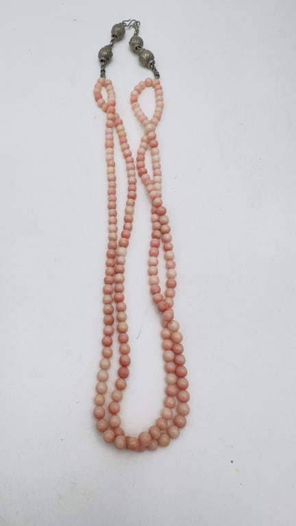 A charming multi-strand necklace composed of polished round coral beads, ranging in soft shades: A charming multi-strand necklace composed of polished round coral beads, ranging in soft shades from pale peach to deeper pinkish-red tones. The coral beads display natural variation and warmth, elega