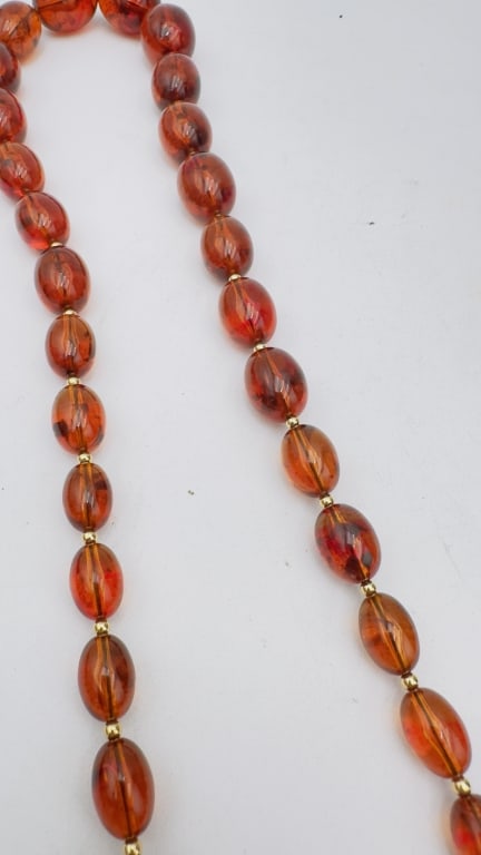 A fine necklace composed of graduated oval amber beads, each exhibiting rich cognac and cherry-red (1 of 5)