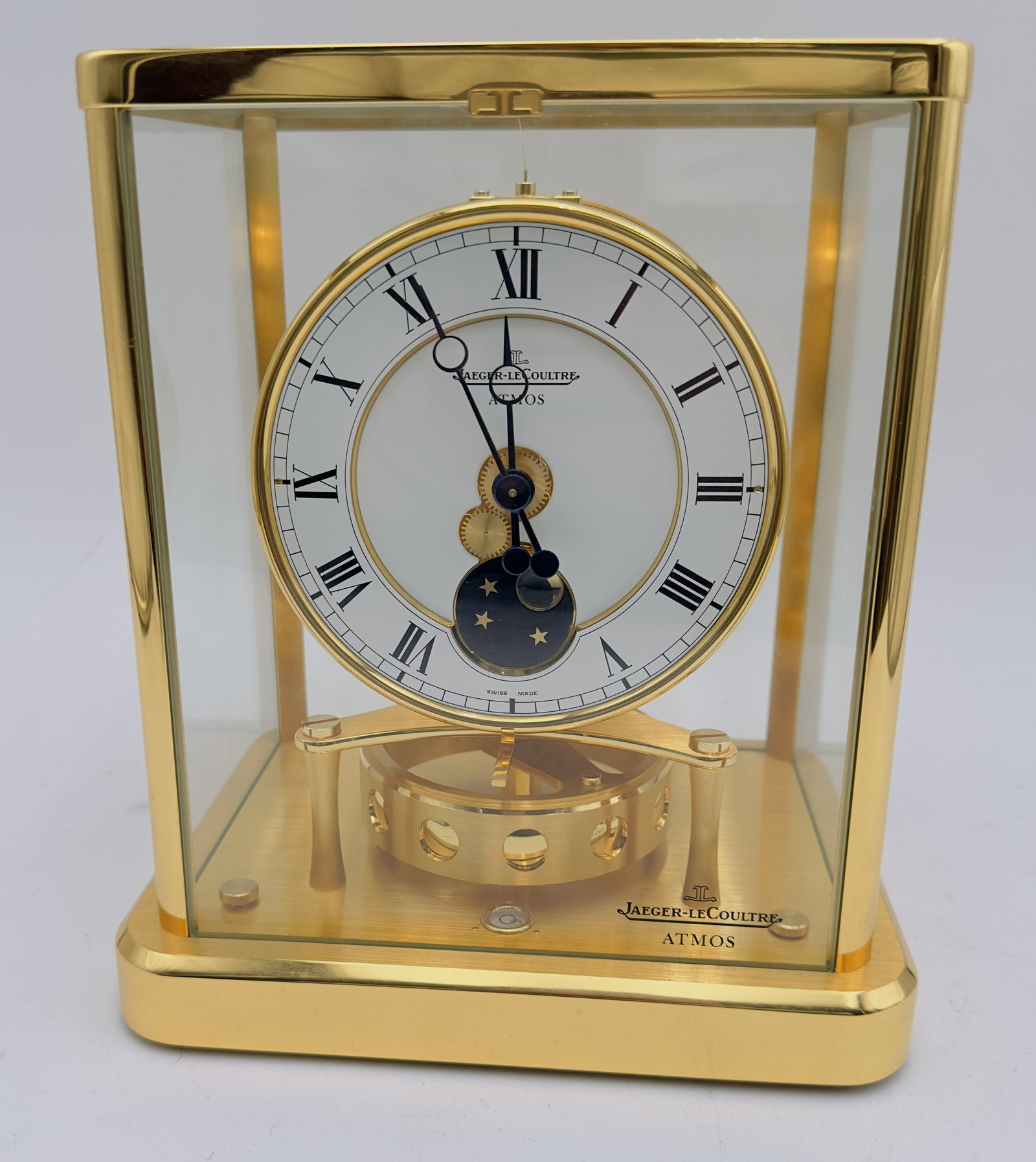 Jaeger LeCoultre | ATMOS WITH MOON PHASE MADE OF GLASS AND BRASS: Jaeger LeCoultre.Technique: Glass, gilt brass a.o.Description: Glazed case. White lacquered dial with Roman numerals. Calibre 540. Rotating pendulummovement with winding through membranes by means of