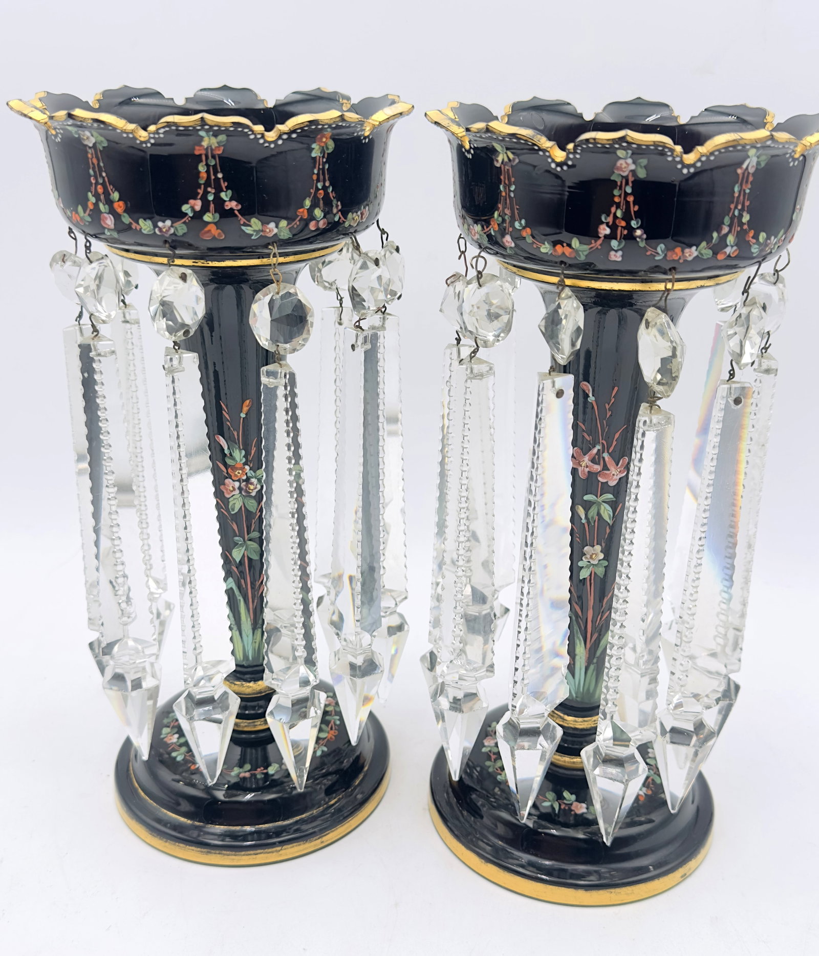 Pair of Bohemian Black Glass Lustres with Hand-Painted Enamel & Crystal Drops: A fine pair of Bohemian black glass lustres, decorated with delicate hand-painted floral enamel and gilt accents. Each piece is adorned with hanging cut crystal prisms, creating an elegant Victorian-s