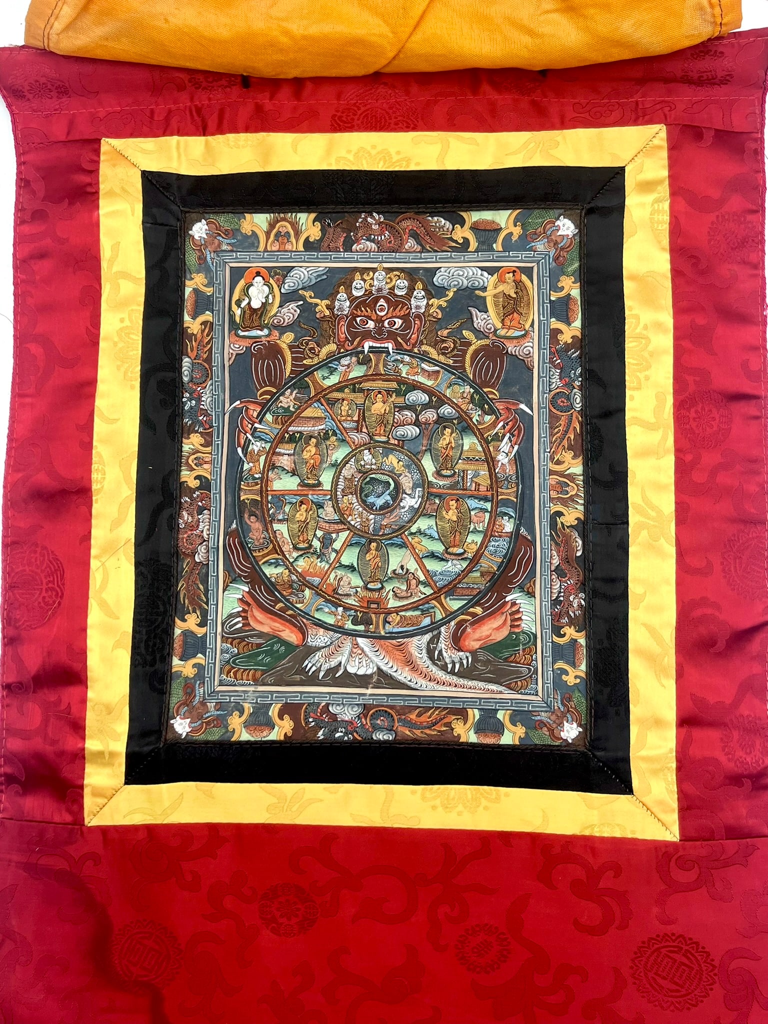 Tibetan Buddhist Thangka Scroll Painting, Wheel of Life Motif: A finely detailed Tibetan Buddhist thangka scroll painting depicting the Wheel of Life (Bhavachakra) motif, richly rendered with intricate symbolic figures, deities, and traditional iconography. The