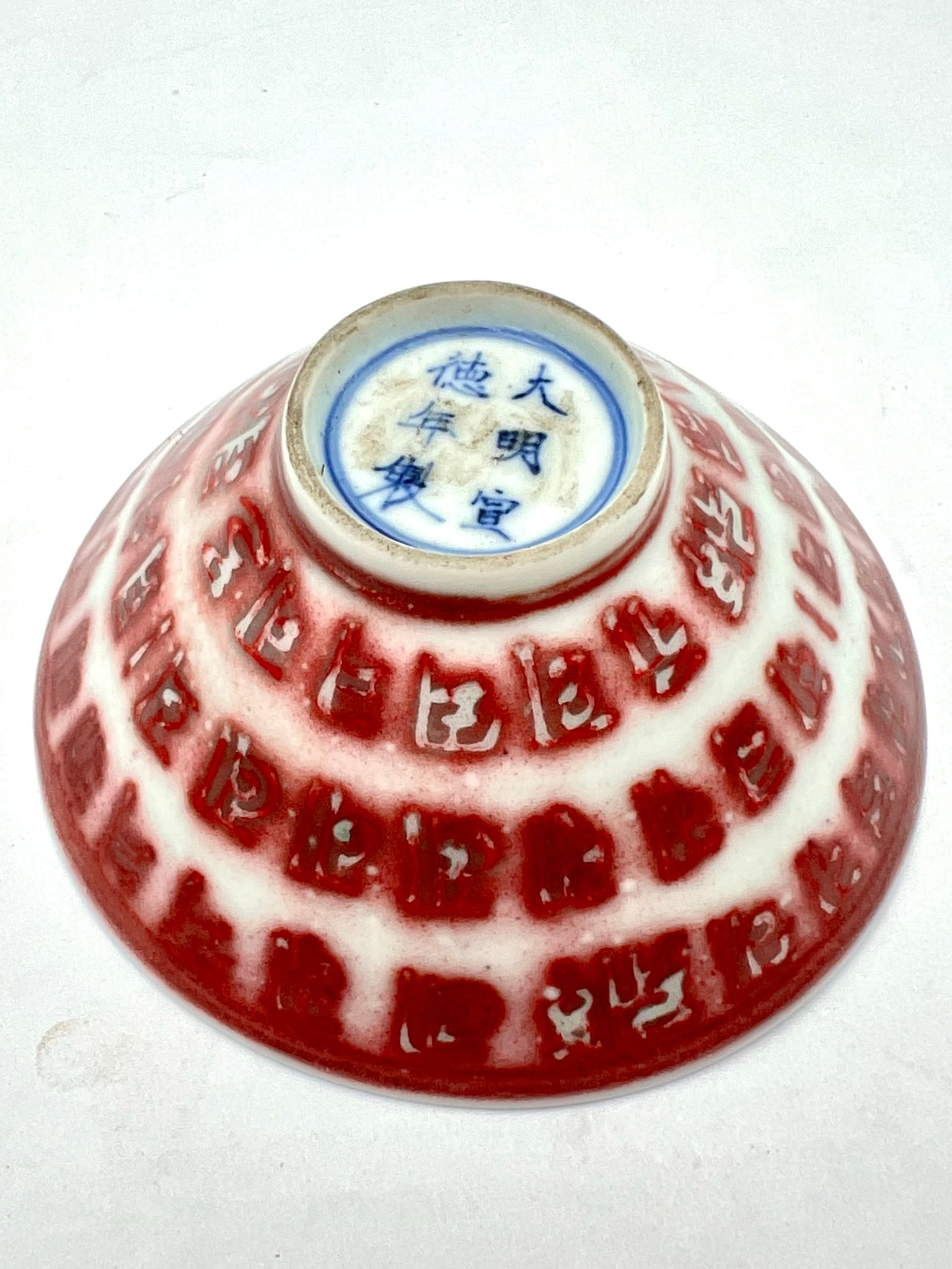 Chinese Red & White Porcelain Bowl with Script Decoration Da Ming De Hua Nian Zhi: Chinese porcelain bowl decorated in red relief with stylized archaic script motifs arranged in concentric bands. The base bears a blue underglaze six-character Xuande reign mark (Da Ming Xuande Nian Z