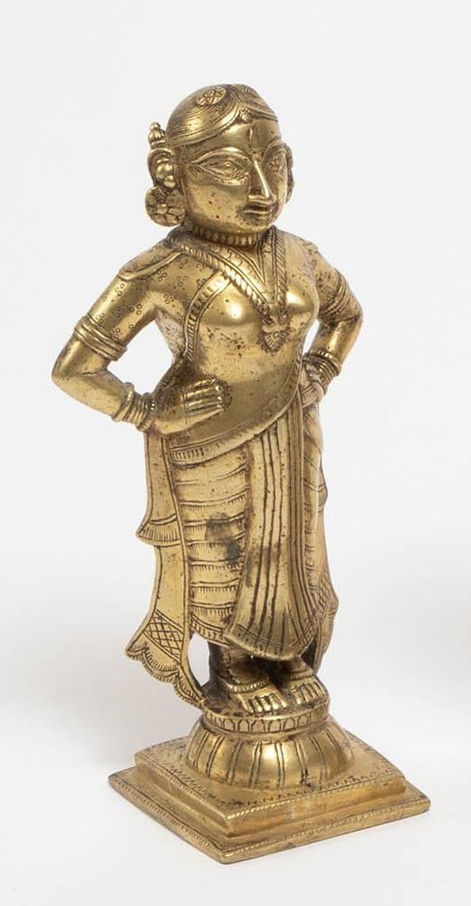 An Indian brass figure depicting a standing female deity, shown in traditional attire with (1 of 3)