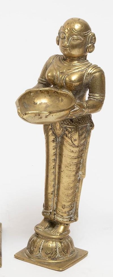 An Indian brass figure depicting a standing female attendant holding a bowl with both hands. The (1 of 3)