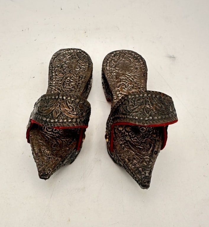 A rare and finely crafted pair of Ottoman silver repouss' kabkab sandals: A rare and finely crafted pair of Ottoman silver repoussé kabkab sandals, each of traditional pointed form with high platform base and arched strap. The entire surface is richly decorated with hand-c