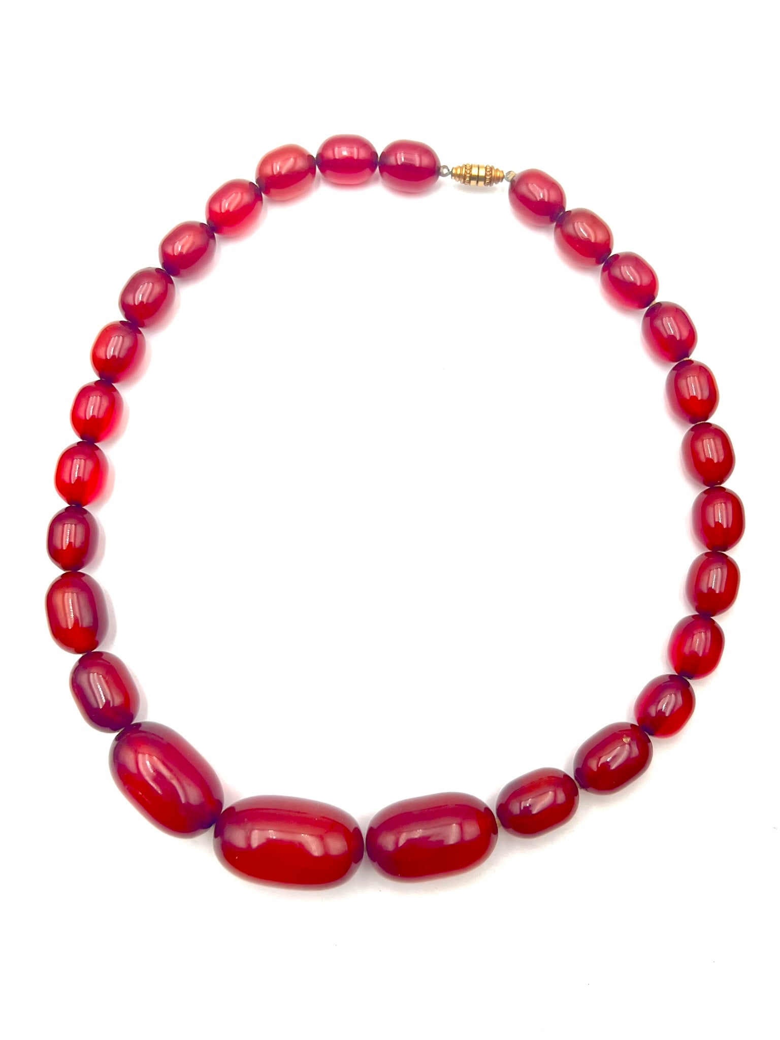A Vintage Bakelite Graduated Red Bead Necklace: Vintage Bakelite necklace composed of graduated translucent deep red beads, polished in elongated oval and rounded forms, strung in a balanced tapering design. Featuring rich cherry-red coloration wit