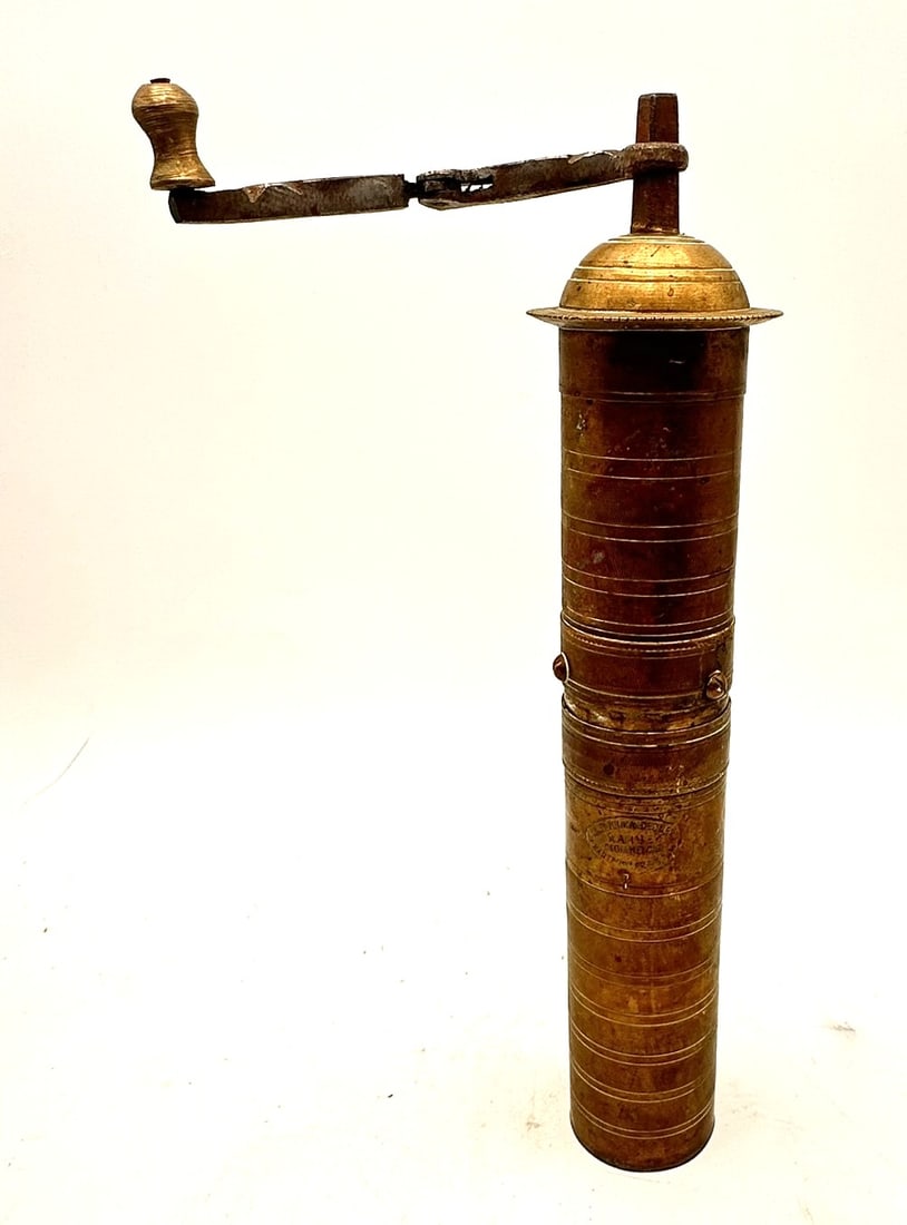A finely crafted brass hand-crank coffee grinder, cylindrical in form with a hinged domed lid and: A finely crafted brass hand-crank coffee grinder, cylindrical in form with a hinged domed lid and folding iron handle with turned brass finial. The body is decorated with incised concentric rings and 