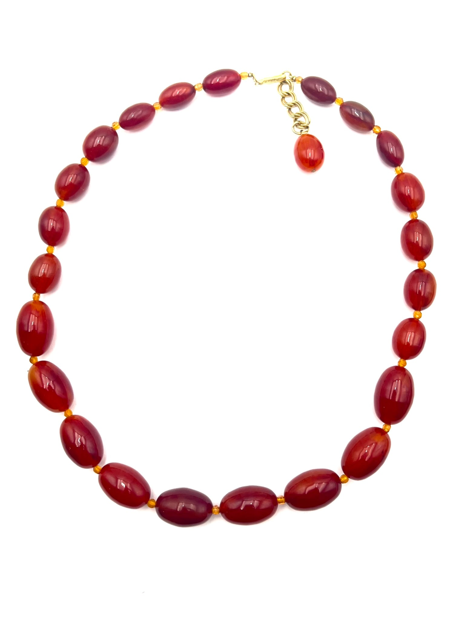 Bakelite Bead Necklace: A vintage jewelry set featuring marbled reddish-orange Bakelite-style oval beads with a polished finish and warm translucent tones. The necklace is accented with small amber-tone spacer beads and acco