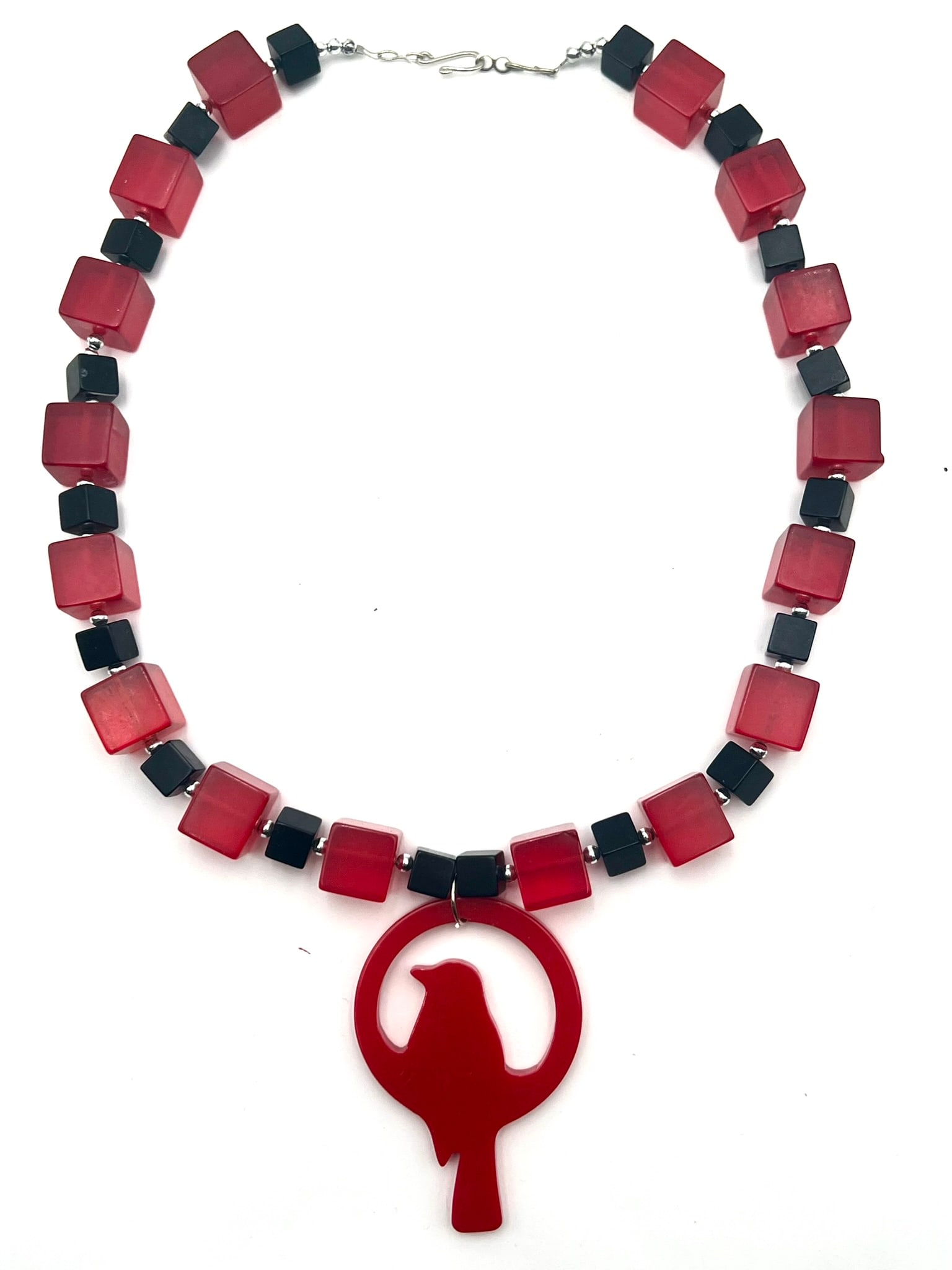 Bakelite Geometric Pendant Necklace: A striking vintage-style necklace featuring translucent red Bakelite beads in cube form, accented by contrasting black geometric spacer beads and polished metal separators. Centered with a large styli