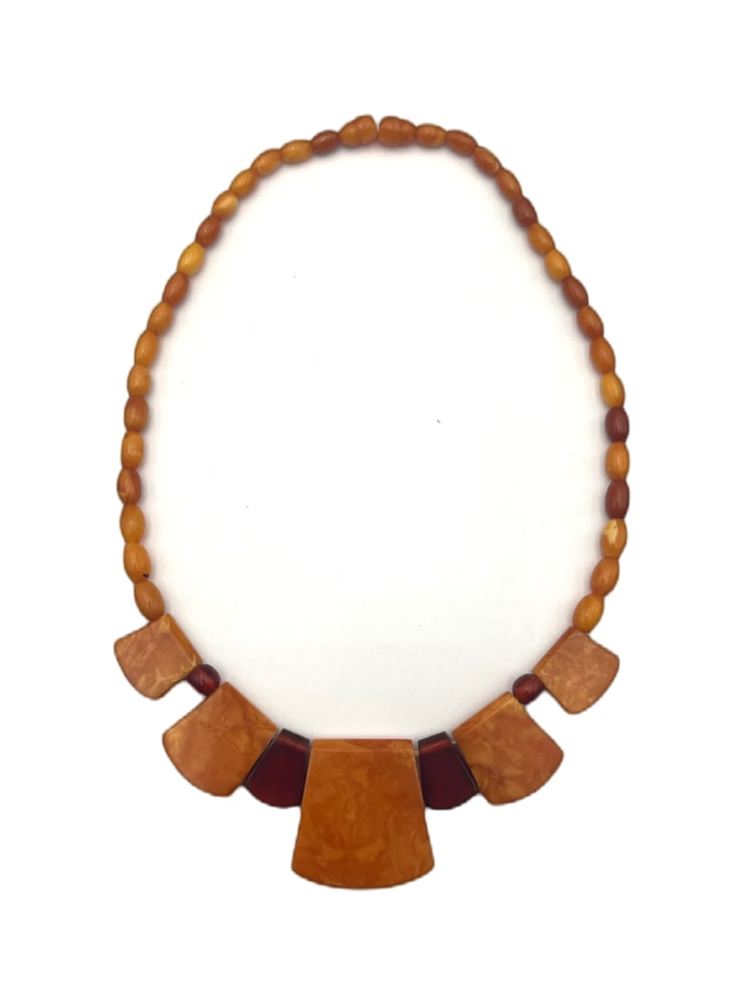 Art Deco Butterscotch Amber Bakelite Necklace: A striking Art Deco style necklace composed of graduated butterscotch amber-tone Bakelite panels interspersed with darker translucent spacer elements and strung with matching oval beads. The necklace 
