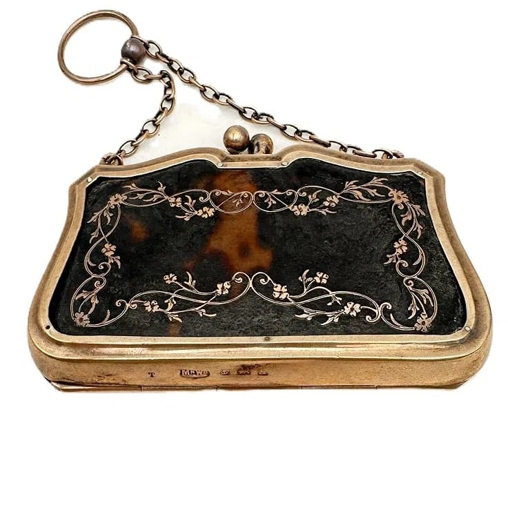 Victorian Silver and faux tortoiseshell Piqu? Purh An elegant late-19th-century English: An elegant late-19th-century English silver-mounted Faux tortoiseshell purse, the curved body delicately inlaid with floral and scroll motifs in gold pique work. Fitted with a silver-gilt frame and ch