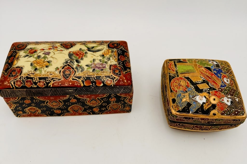 Pair of Japanese Hand-Painted Ceramic Boxes, Meij) A charming pair of finely decorated Japanese: A charming pair of finely decorated Japanese lidded boxes. One rectangular box features a delicate floral and bird motif in gilt and enamel against a black and red ground. The smaller square box depic