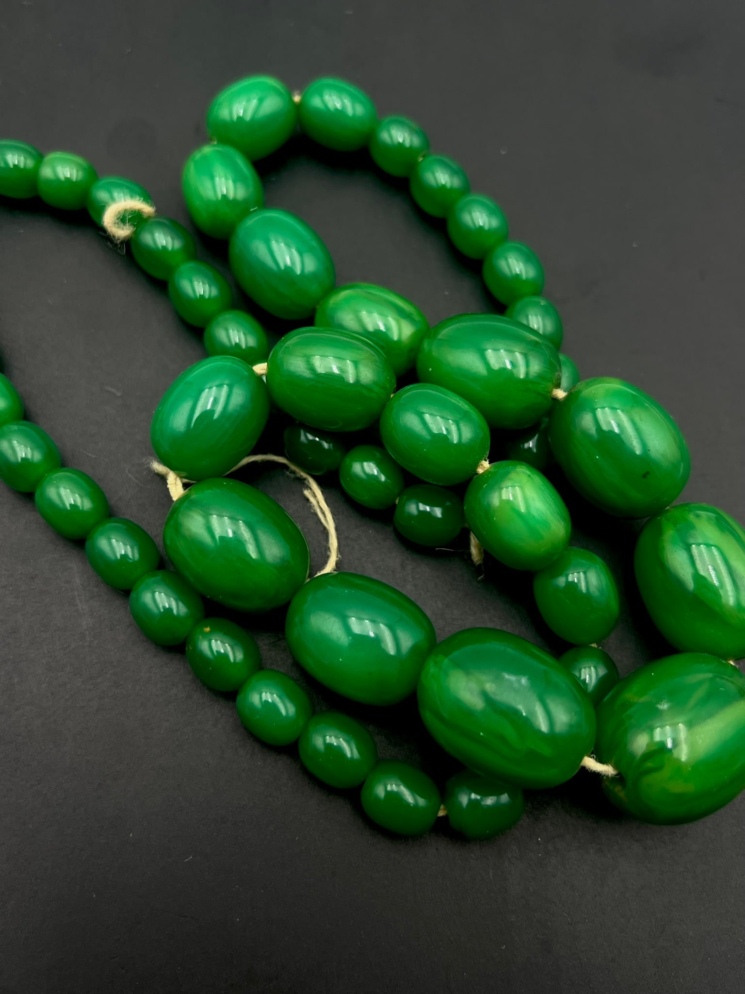 Vintage Red Marbled Bakelite Bead Necklace: A vintage necklace composed of tested red marbled Bakelite beads in a cylindrical graduated form. The beads display rich translucent crimson and orange tones with attractive swirling marbling througho