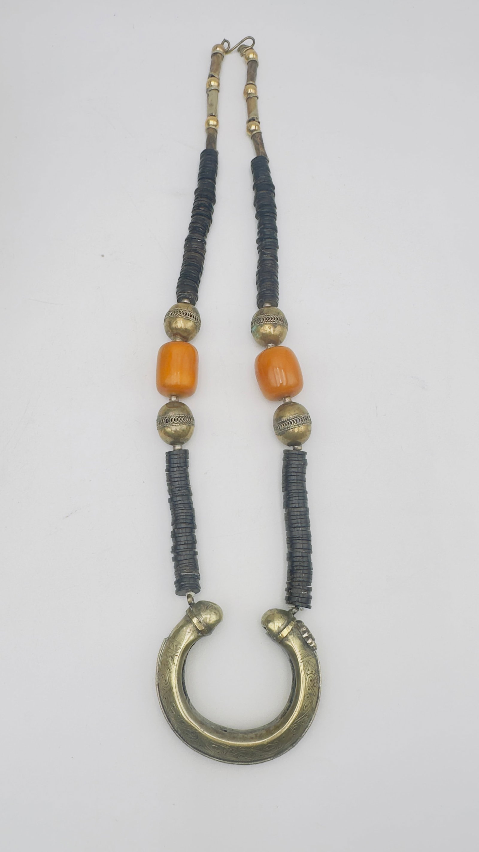 Middle Eastern Silver-Mounted Necklace with Amber bakelite Beads and Engraved Crescent Pendant: A traditional Middle Eastern necklace featuring an engraved crescent-shaped silver-tone pendant suspended from strands of dark disc beads accented with silver-tone filigree beads and two large amber-c