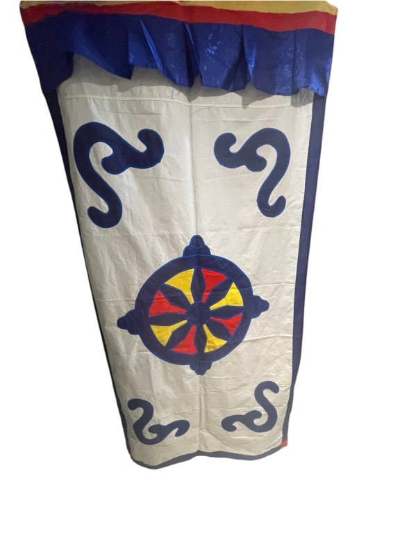 Large Tibetan Buddhist Temple Banner with Dharmace Object Type: A large-scale Tibetan Buddhist: Object Type: A large-scale Tibetan Buddhist temple banner featuring a central appliqued Dharmachakra (Wheel of Dharma).Design & Motifs: The white canvas ground showcases a vibrant multicolored Wheel o