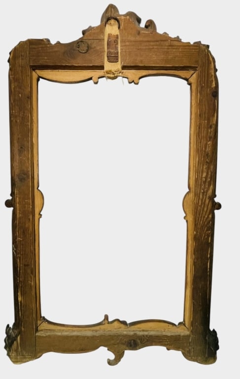 AN ORNATE CARVED GILTWOOD ROCOCO-STYLE PICTURE ORY An elaborate carved wood frame of rectangular: An elaborate carved wood frame of rectangular form, richly decorated in the Rococo taste with scrolling foliate motifs, shell-form ornament and pierced carved cresting. The shaped upper and lower rail