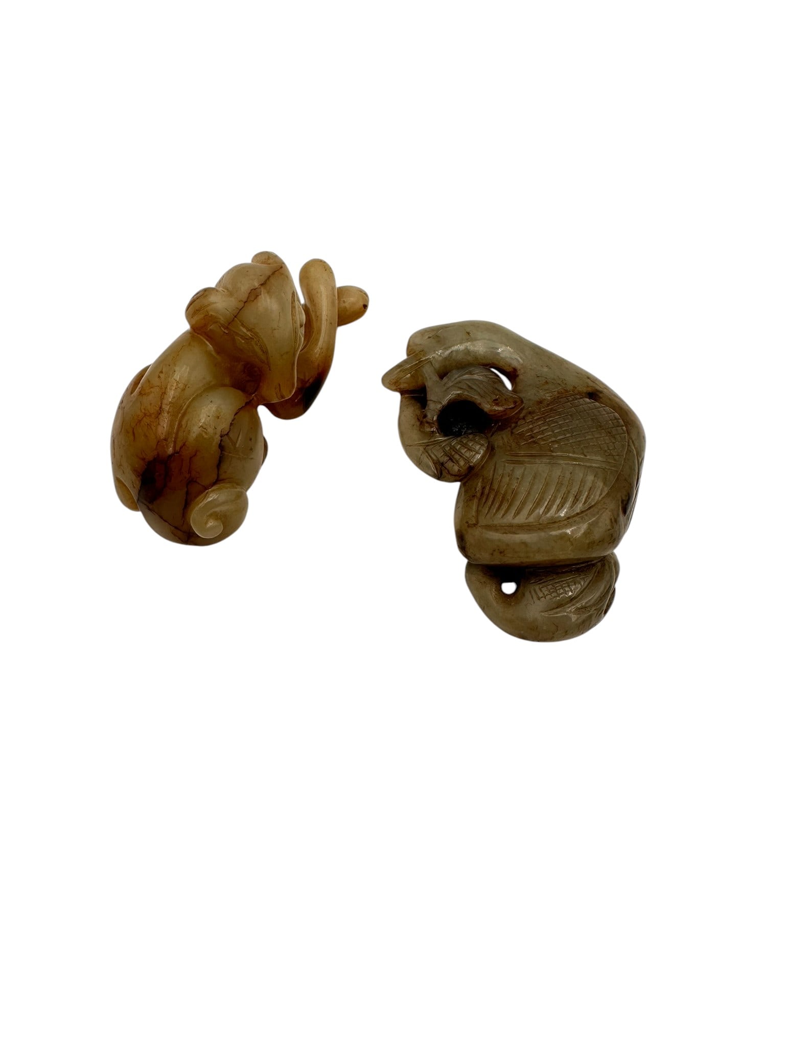 Carved Jade Ornaments A pair of Chinese jade animal carvings, . Each carved in a stylized manner: A pair of Chinese jade animal carvings, . Each carved in a stylized manner with large rounded eyes and exaggerated features, one seated upright with paw raised, the other recumbent with head turned. T