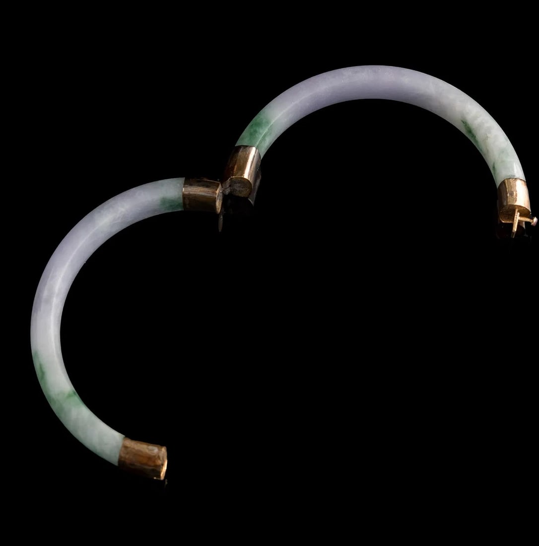 CHINESE LAVENDER AND GREEN JADEITE BANGLE BRACELES A Chinese polished jadeite bangle bracelet: A Chinese polished jadeite bangle bracelet displaying pale lavender coloration with mottled green areas, constructed in sections and fitted with gold hinged mounts and clasp.Material: Jadeite, mounts: