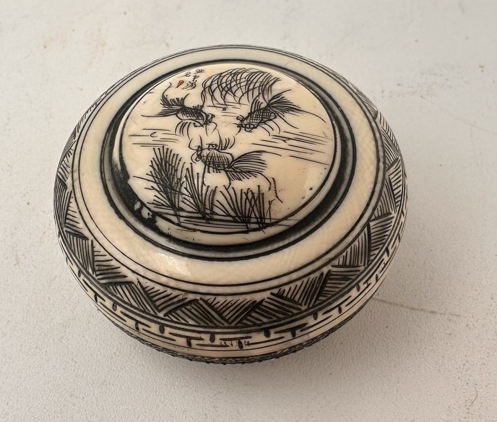 Chinese Carved Ivory Circular Box with signture Chinese Carved Ivory Circular Box with signture: Chinese Carved Ivory Circular Box with signture Mark, Late Qing?Republic Period (c. 1900)Of circular form with fitted lid, finely engraved with a bird among reeds, the decoration highlighted with blac