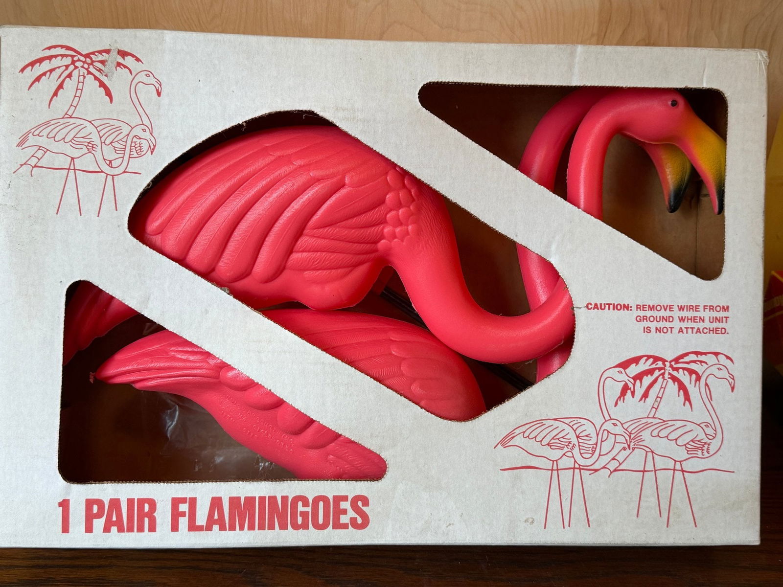Pair of Pink Plastic Lawn Flamingo Ornaments in Original Box: This classic pair of pink plastic lawn flamingos comes in its original retail packaging, featuring the iconic vibrant pink color and traditional posing. Each flamingo includes its distinctive yellow a