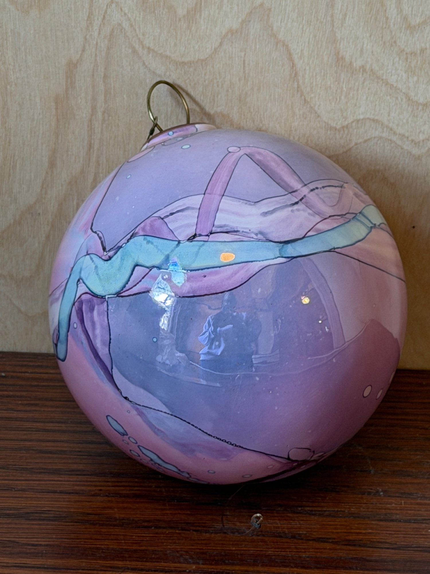 Art Glass Hand-Painted Ornament with Swirl Abstract Design: This stunning art glass ornament features a vibrant, hand-painted abstract design with swirling patterns of purple, pink, and teal blue. The spherical piece is accented with delicate line work and iri
