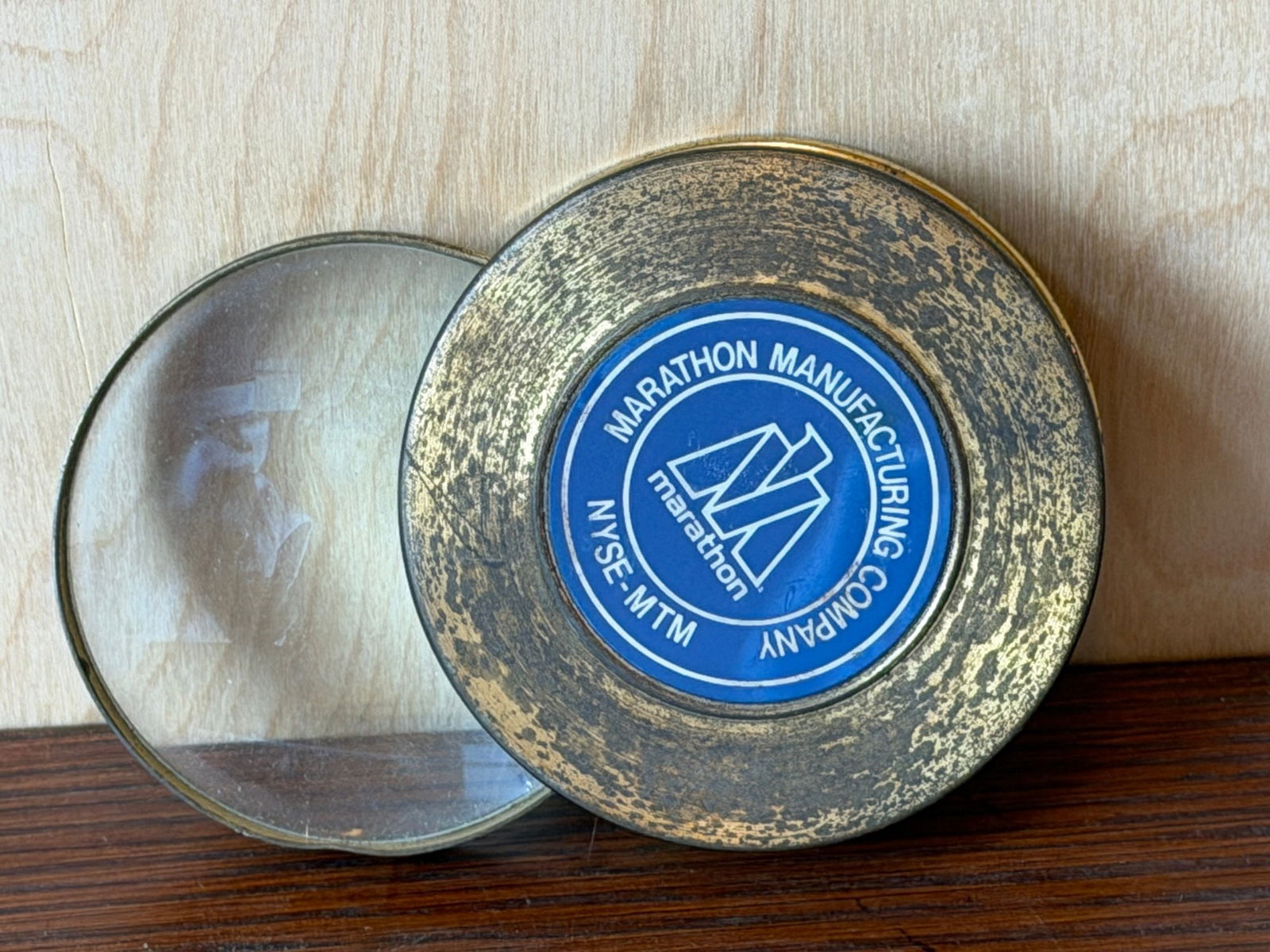 Vintage Marathon Manufacturing Company Pocket Magnifying Glass: This vintage pocket magnifying glass features a swing-out lens housed in a brass-tone circular casing. The front is prominently marked with the blue and white logo for the Marathon Manufacturing Compa