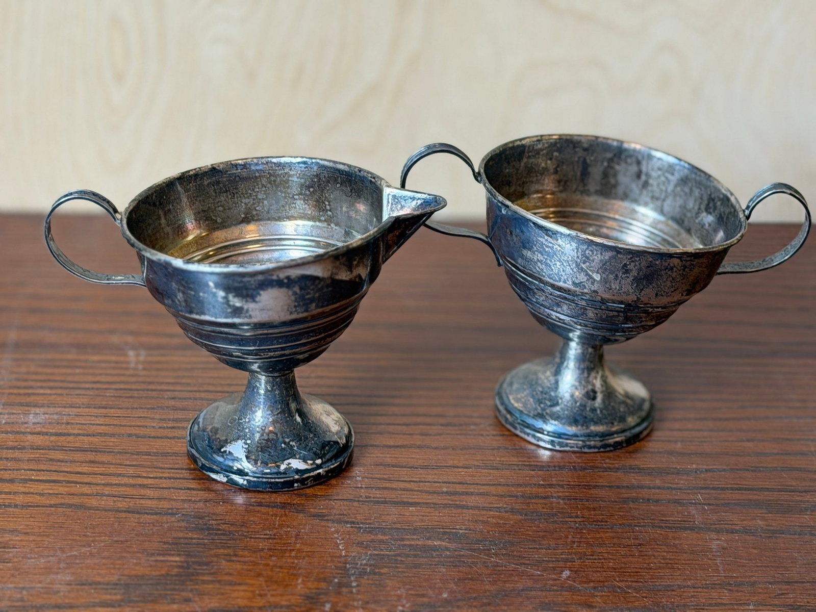 Silver Creamer and Sugar Bowl Set: This is a matching vintage sterling silver creamer and sugar bowl set. Both pieces feature a classic pedestal base with a ribbed or tiered body design and curved handles. The creamer includes a small 